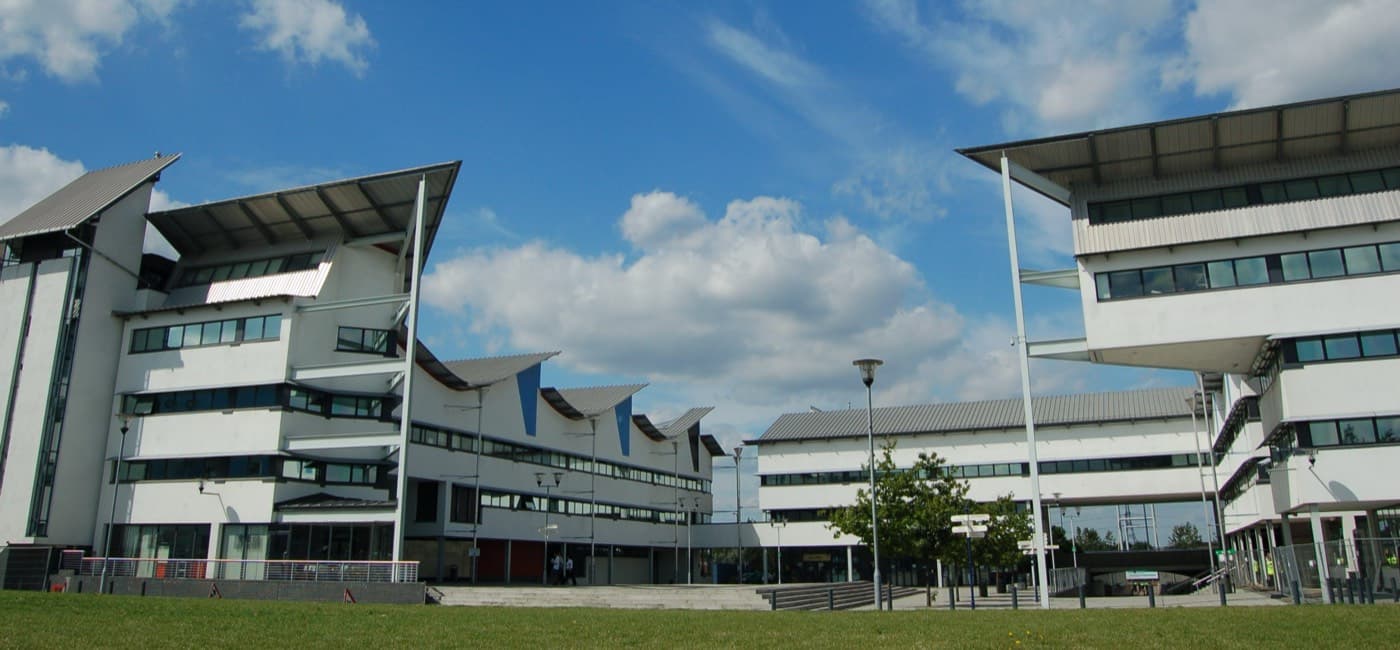 Docklands kampüsünün kanatlı çatılı modern binaları ve önündeki meydan, University of East London