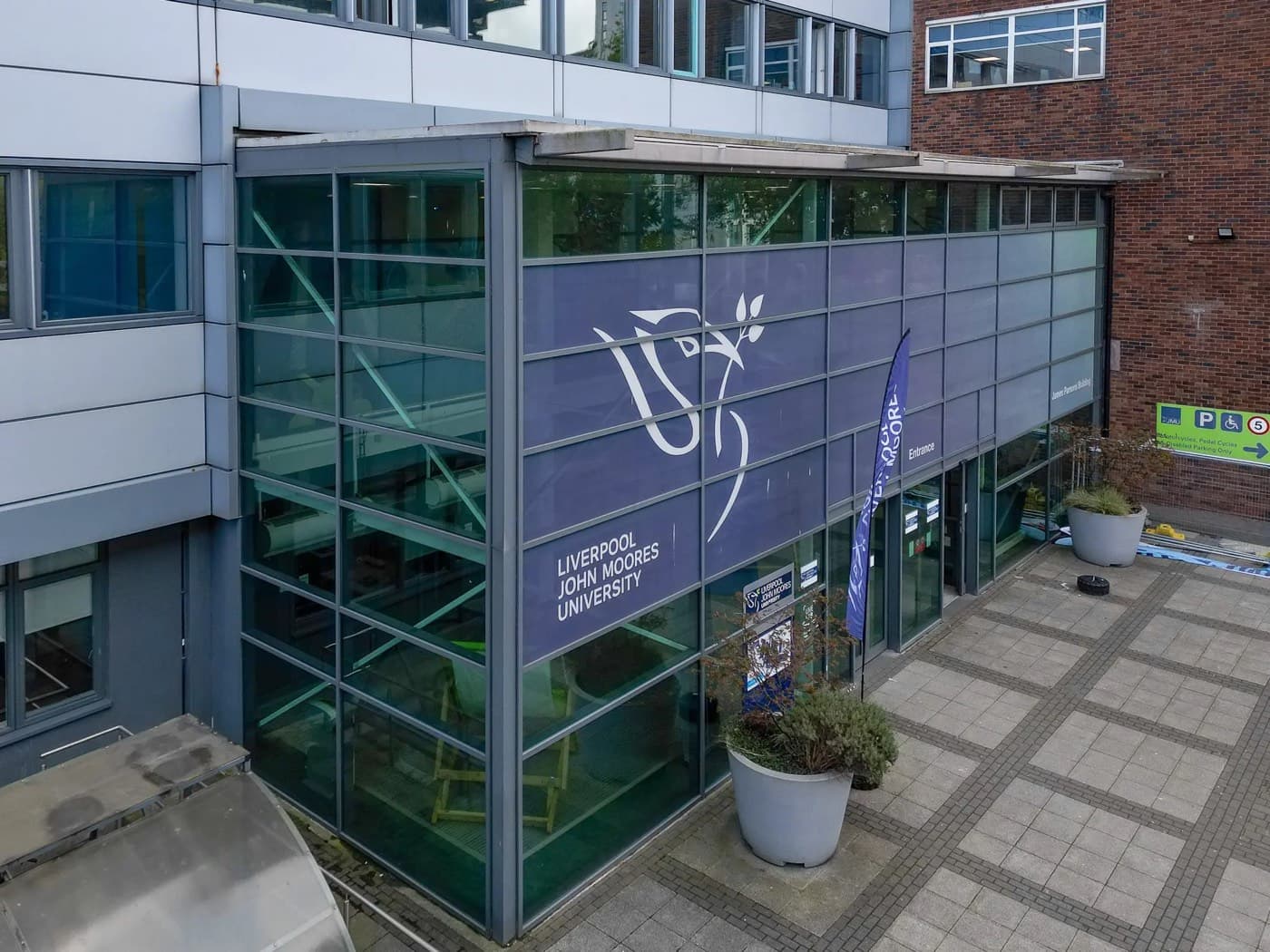 James Parsons Building’in cam giriş cephesi ve üniversitenin liver bird logosu, Liverpool John Moores University