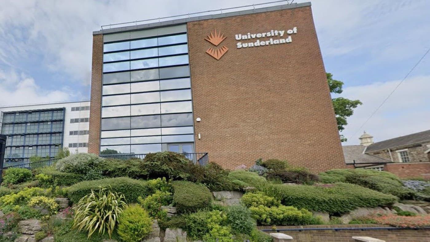 Üniversitenin logosunu taşıyan tuğla cepheli kampüs binası ve önündeki kaya bahçesi, University of Sunderland