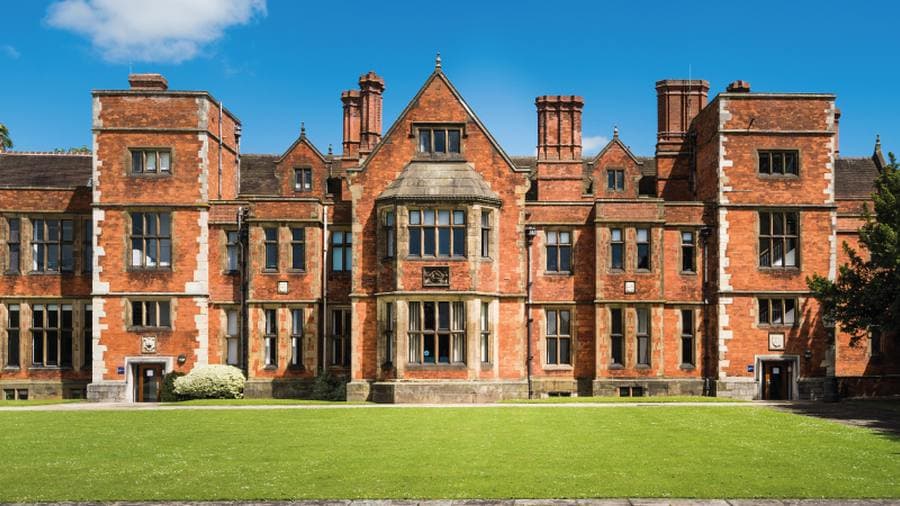 Tuğla cepheli tarihî üniversite binası ve önündeki çim avlu, University of York